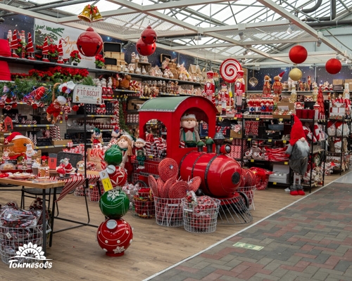 Marché de Noël avec décorations festives et village Lemax en vitrine.